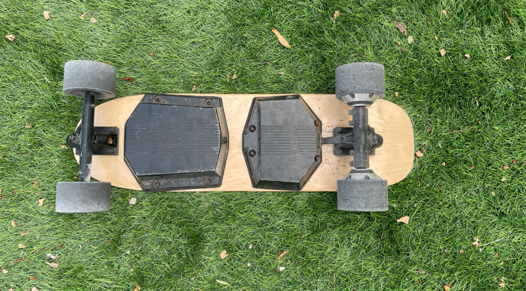 Image skate électrique posé dans l'herbe avec une vision sur les moteurs et la batterie