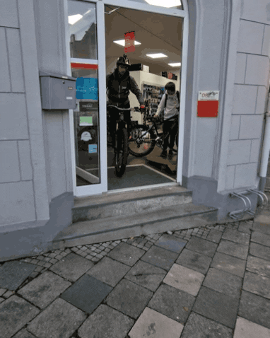 Un homme avec un casque fait un saut en vélo électrique en sortant d'un magasin de vélo